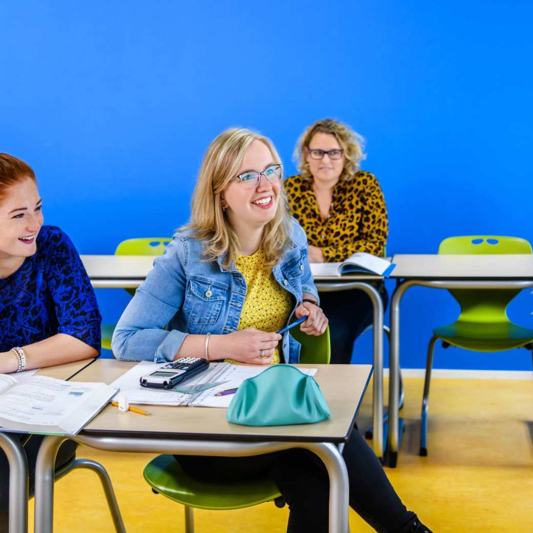 Vier studenten Leraar Duits werken in een klaslokaal aan tafel met laptops
