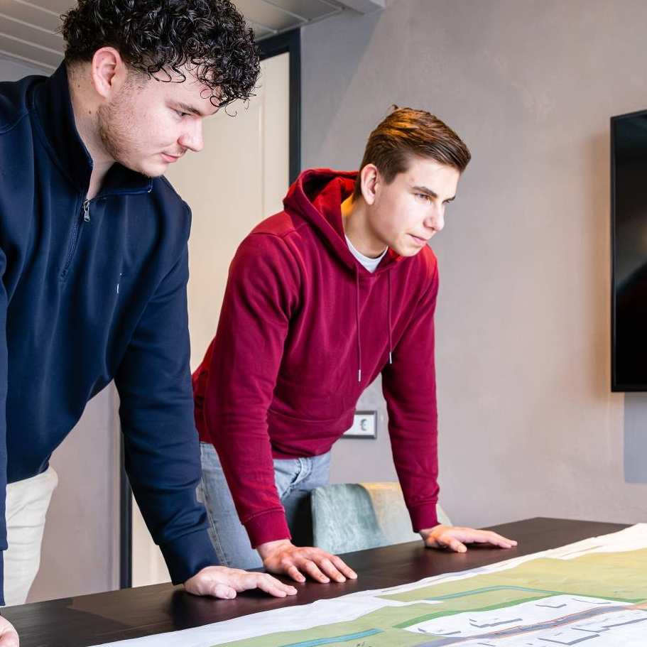 Twee mannen leunen op een bureau met daarop een omgevingskaart.