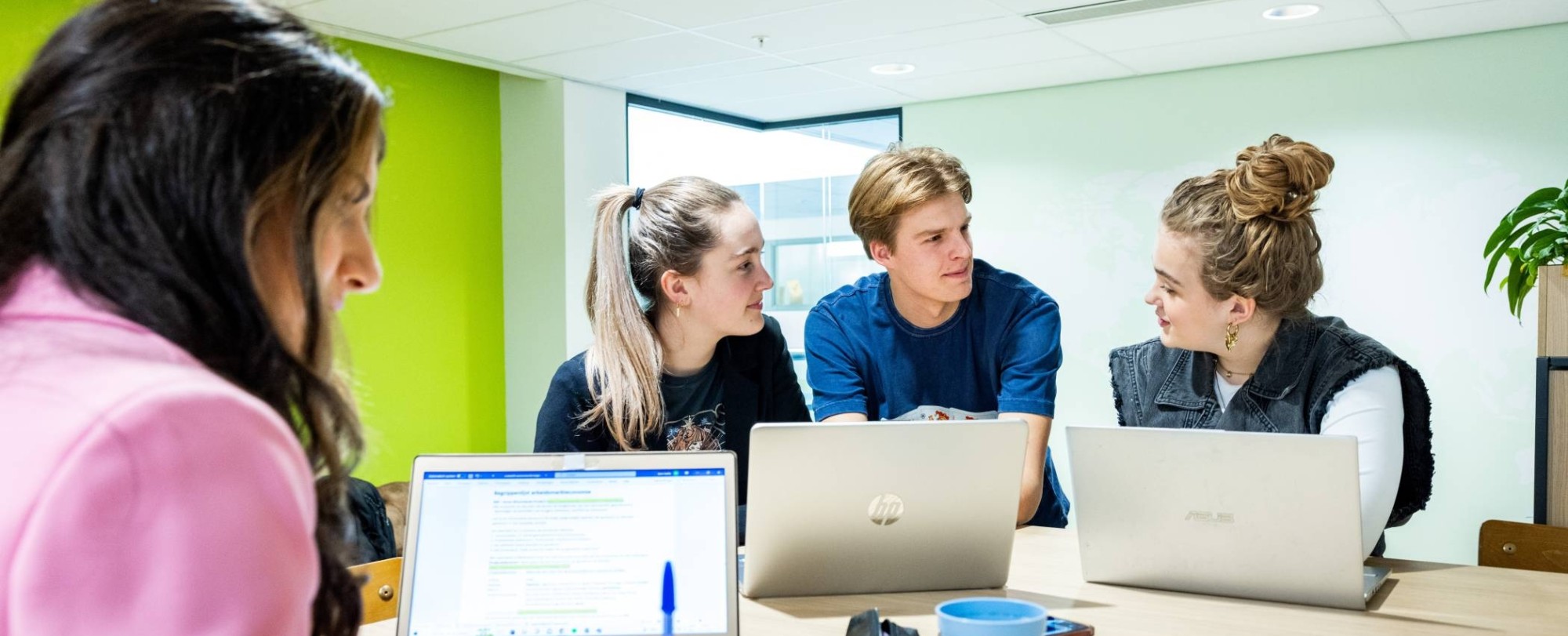 Studenten Human Resource Management (HRM) overleggen in de studio met de laptop erbij