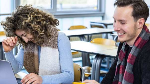 2 studenten Social Work lachen tijdens een college.