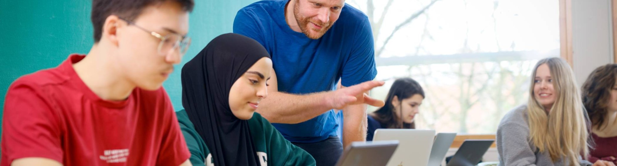 Studenten kijken lachend naar een iPad