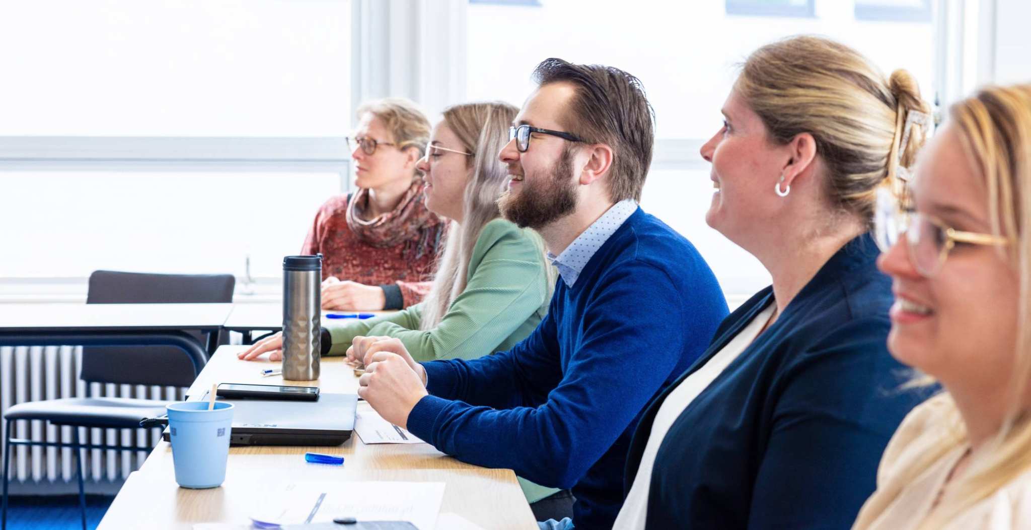 man en vier vrouwen luisteren naar presentatie. Man is aan het lachen. Op de Groenewoudseweg. Opleiding maag-, darm-, leverpleegkundige