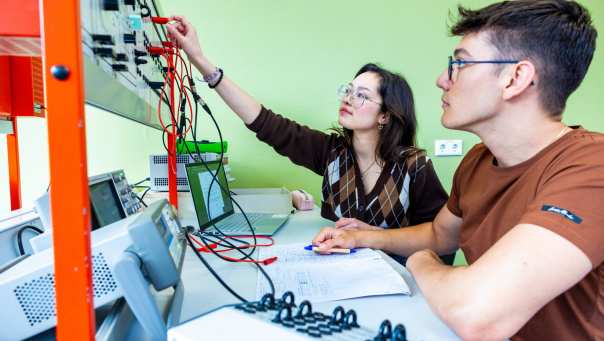 Twee studenten elektrotechniek werken samen tijdens een practicumsituatie.