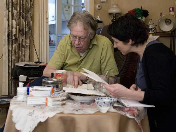 verpleegkundige van de thuiszorg controleert met een patient de medicijnlijsten van de apotheek