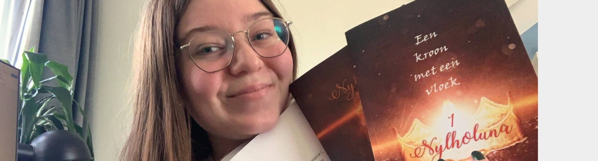 CMD-student Jade Vermeulen heeft haar eigen geschreven boeken in haar handen en glimlacht