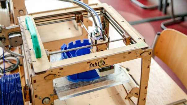 Detailfoto 3D-printer in Fablab met studenten op achtergrond