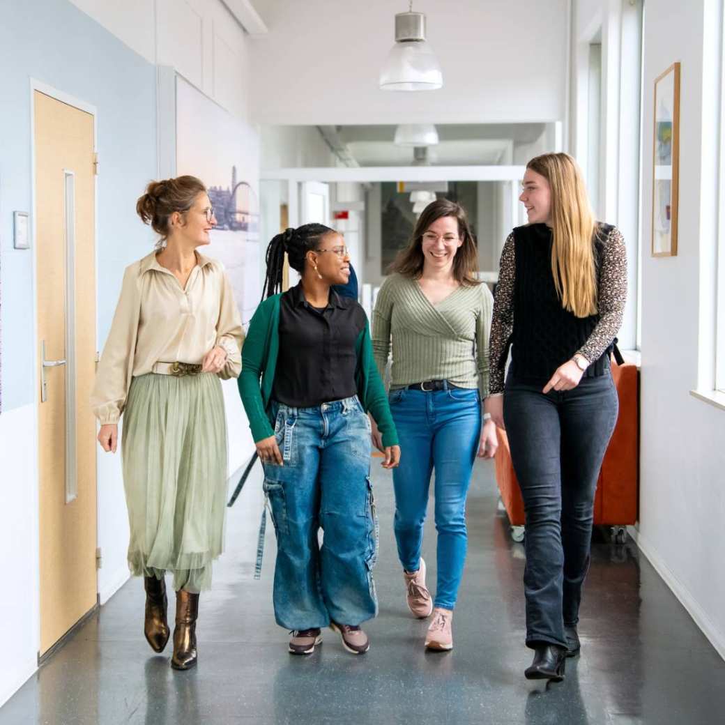 4 vrouwen lopen door de gang