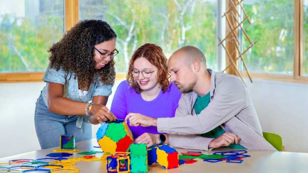 Drie studenten van Leraar Wiskunde maken een bal van puzzelstukken.
