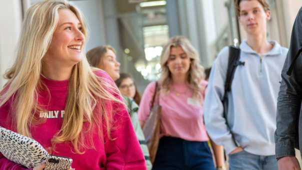 een groepje studenten loopt lachend door de gang