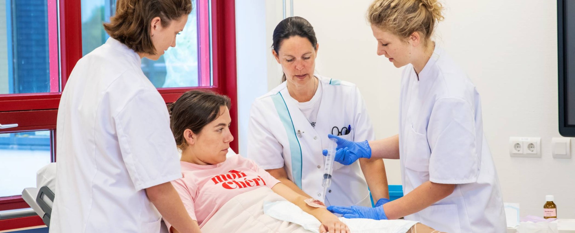 Studenten en docent Verpleegkunde bezig tijdens praktijkles