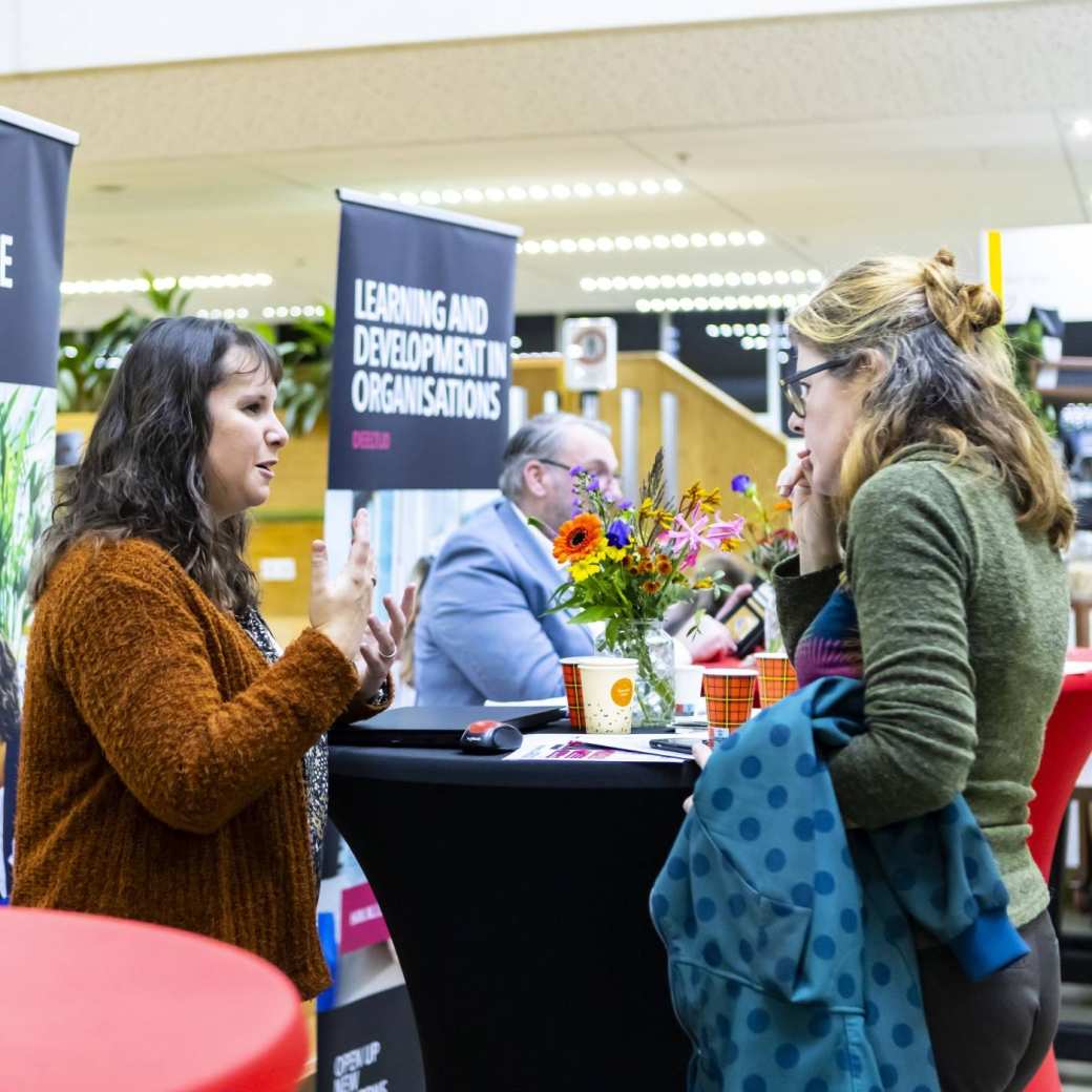 Bezoeker op de Open Avond praat met een medewerker van ASK HAN.