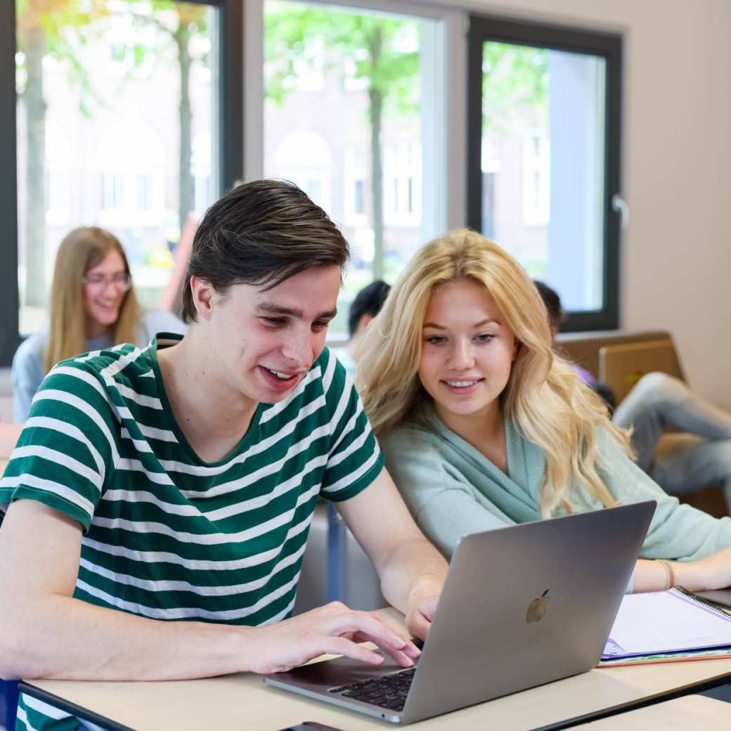 Foto Bedrijfskunde voltijd Nijmegen, klassetting, studenten samenwerken, laptops