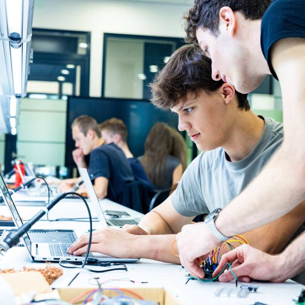 Studenten embedded systems engineering werken samen op de laptop in het lab.