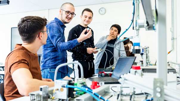 Studenten elektrotechniek krijgen uitleg over een Programmable Logic Controller (PLC).