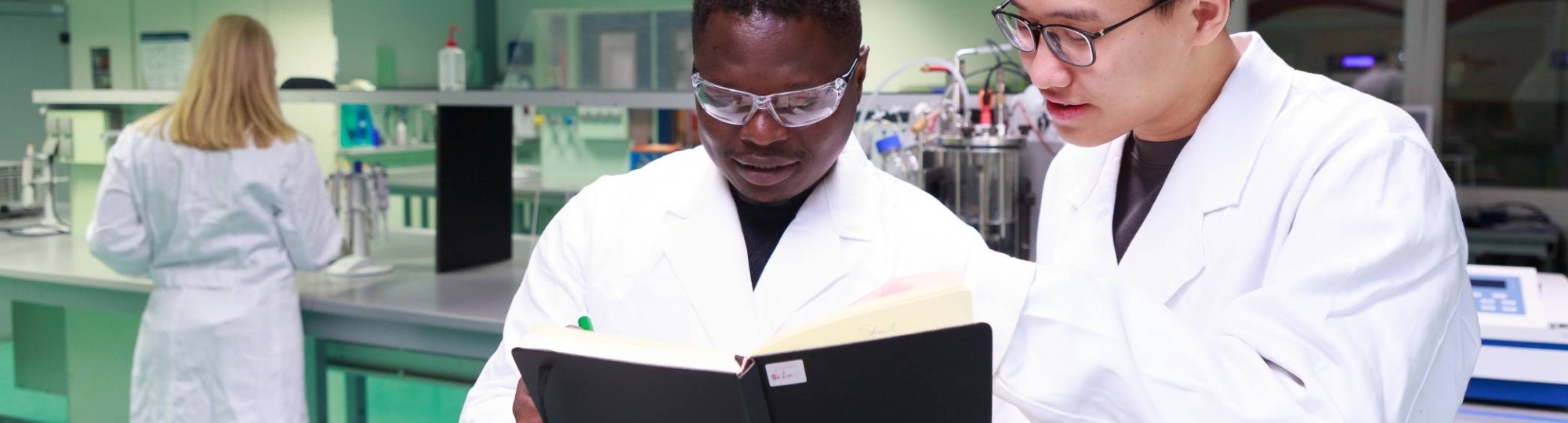 Studenten master Life Sciences Alain Barhasima en Dat Le werken in een biologielab. Op de rug Lisan Scholten