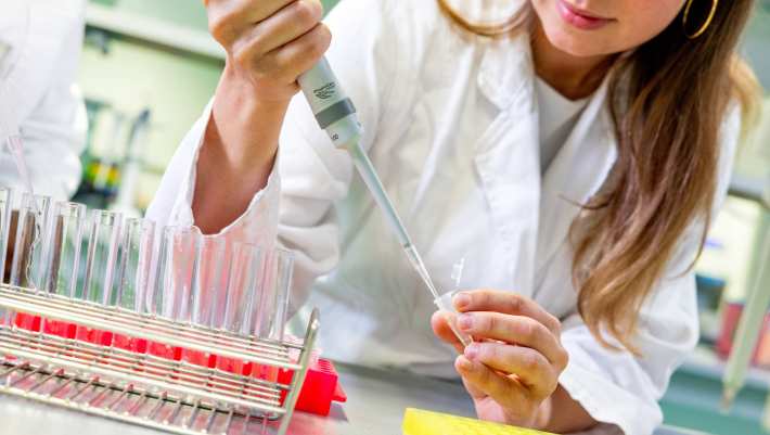 Student in het lab met reageerbuisjes en een pipet