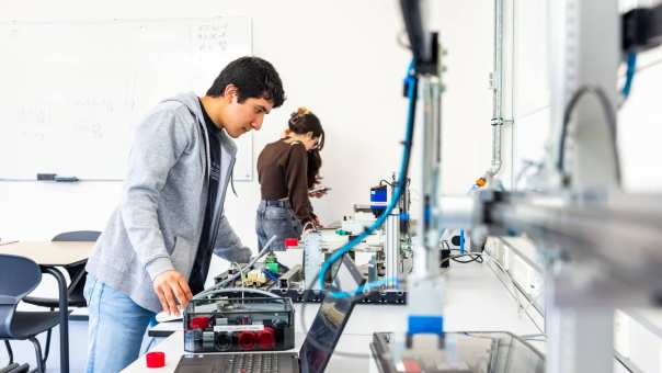 Elektrotechniekstudent Juan werkt aan een PLC in een practicumruimte.