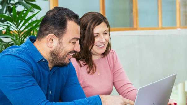 2 masterstudenten zitten lachend met een laptop