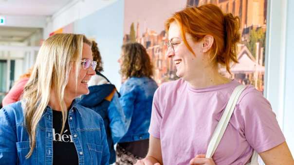 Vrouw laat iets zien op haar mobiel tijdens de cursus acute pijn service. Andere studenten moeten lachen.