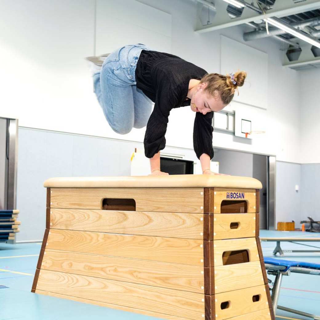 Studente Psychomotorische therapie springt over bank in de gymles tijdens een praktijkles