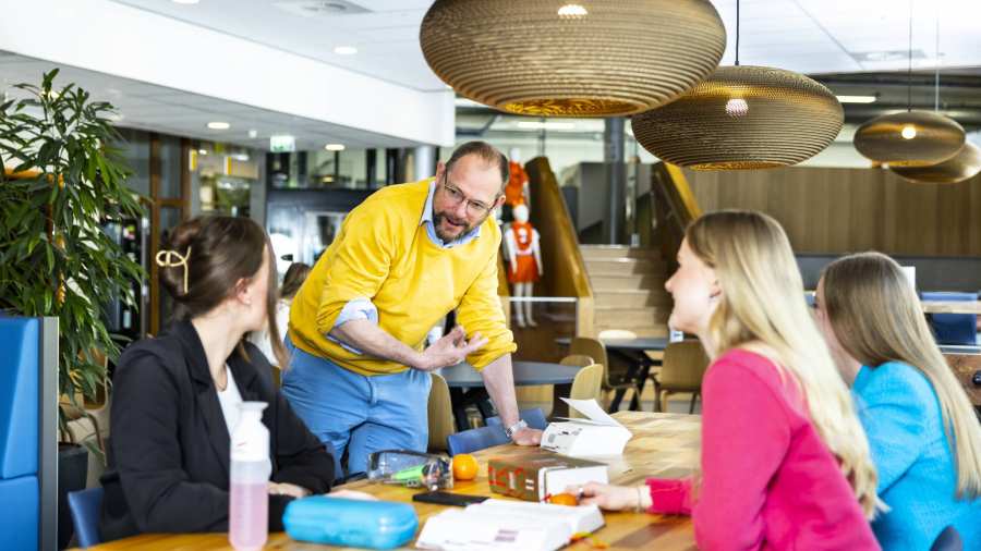 Studenten aan tafel met een docent. 