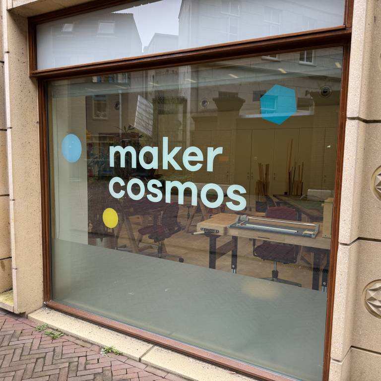 locatie van makercosmos met het logo op het raam