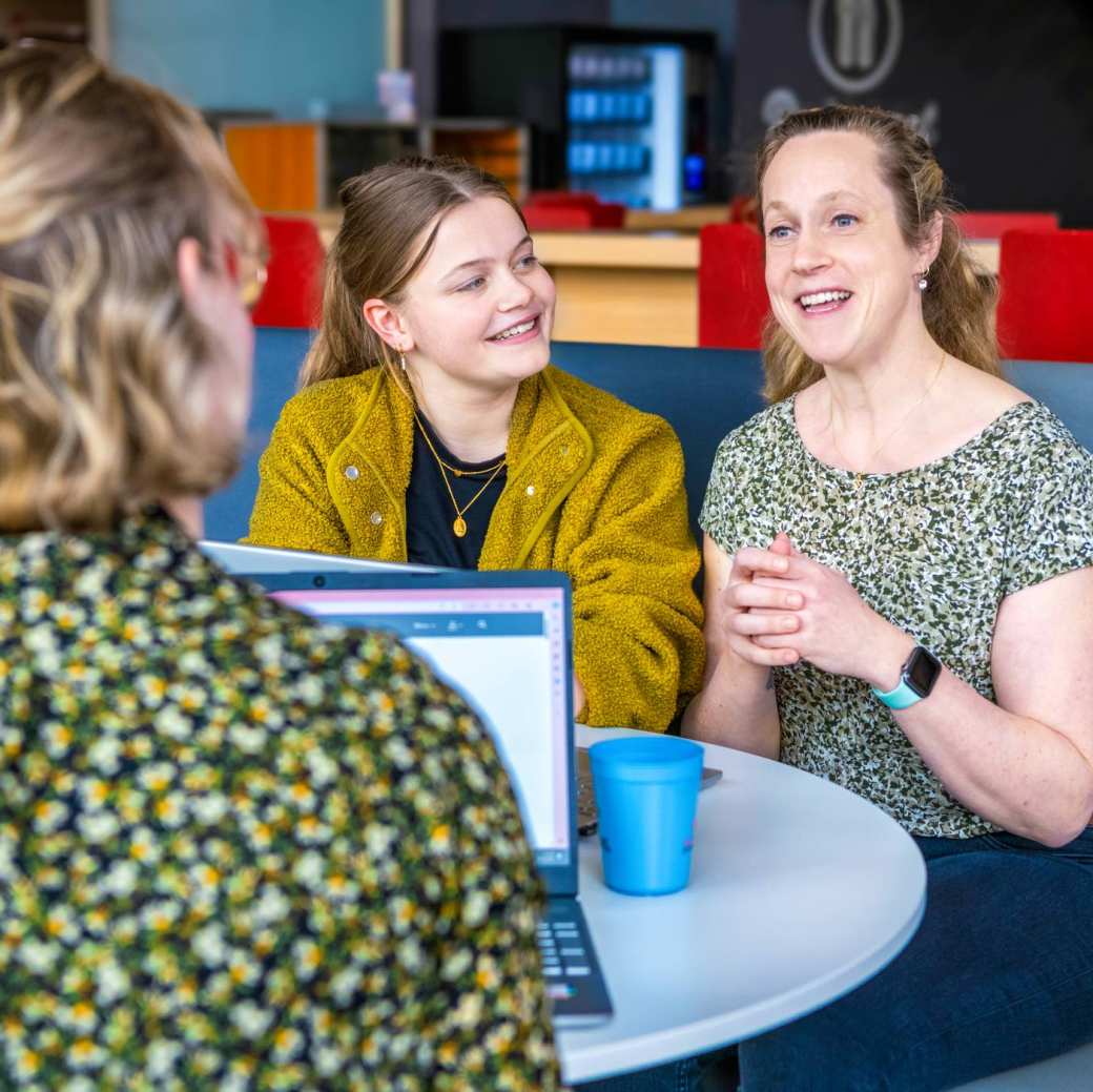 3 studenten met elkaar in gesprek over Verpleegkunde achter de laptop