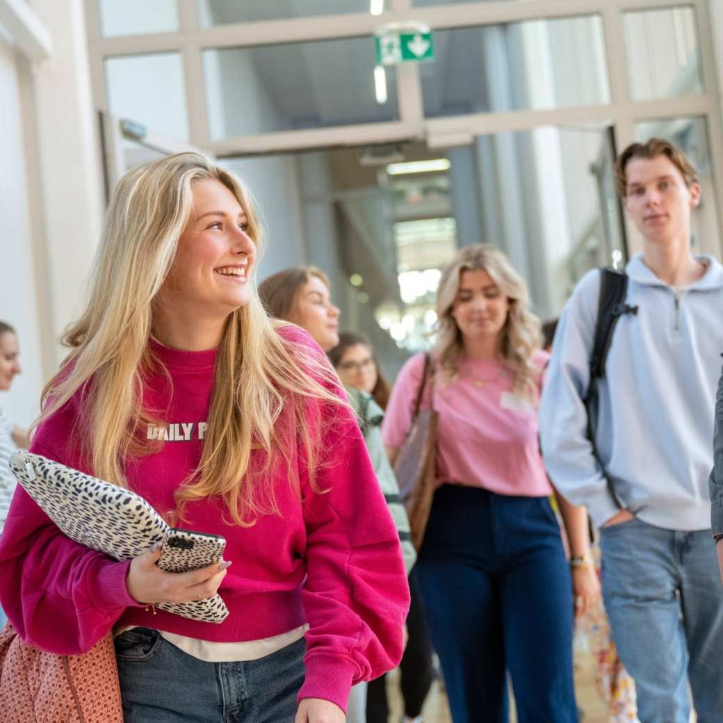 Groepje studenten lopen lachend door de gang van K35 naar K33. 