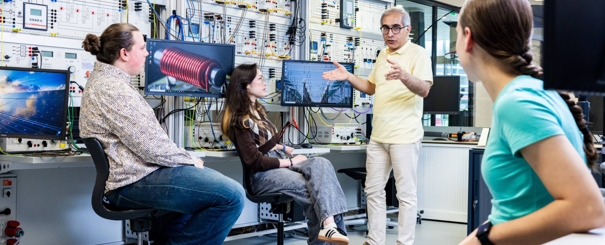 Studenten en docent elektrotechniek tijdens een les in het hoogspanningslab.