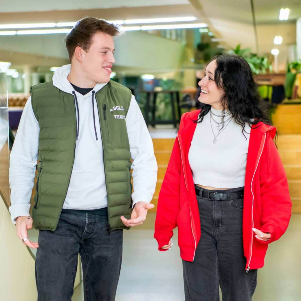 Twee studenten wandelen door de gang.