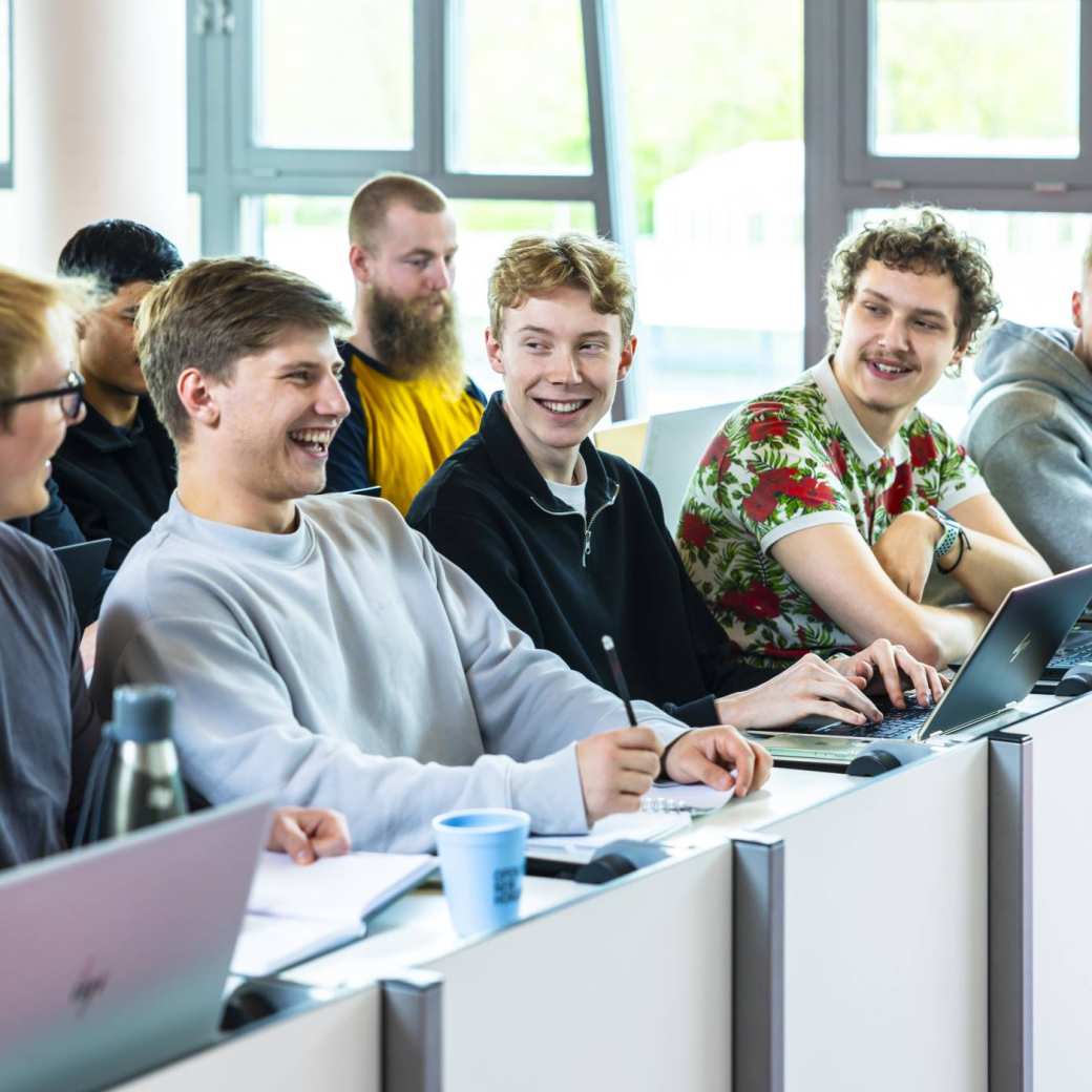 hbo ict studenten zitten lachend in de collegezaal te luisteren naar een docent