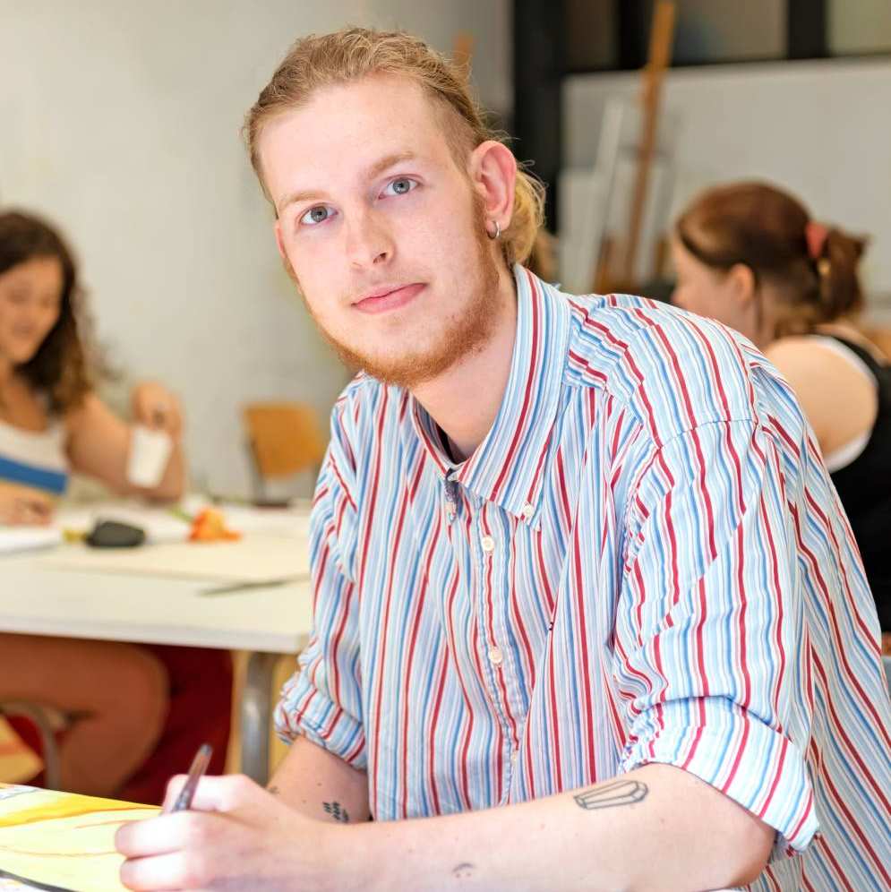 Beeldende therapie student schildert op papier tijdens een praktijkles