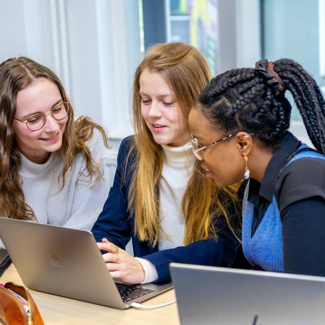 Studenten met laptops, kijken samen op de middelste computer. 