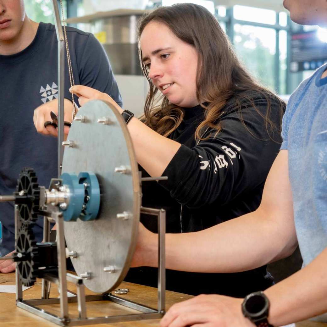 Drie studenten werktuigbouwkunde werken samen aan een kartrol.