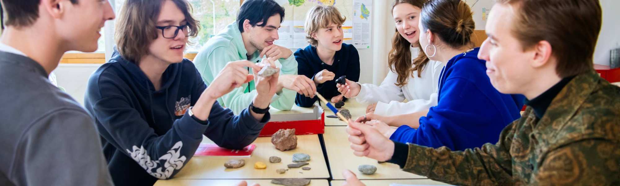 Studenten overleggen samen aan tafel in de klas. 