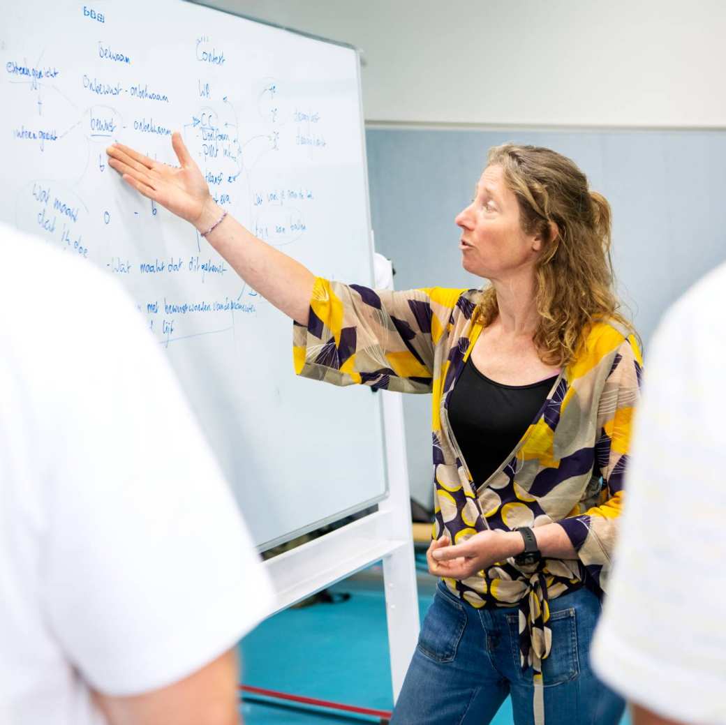 Docent geeft uitleg bij bord aan 2 studenten tijdens les PMT deeltijd