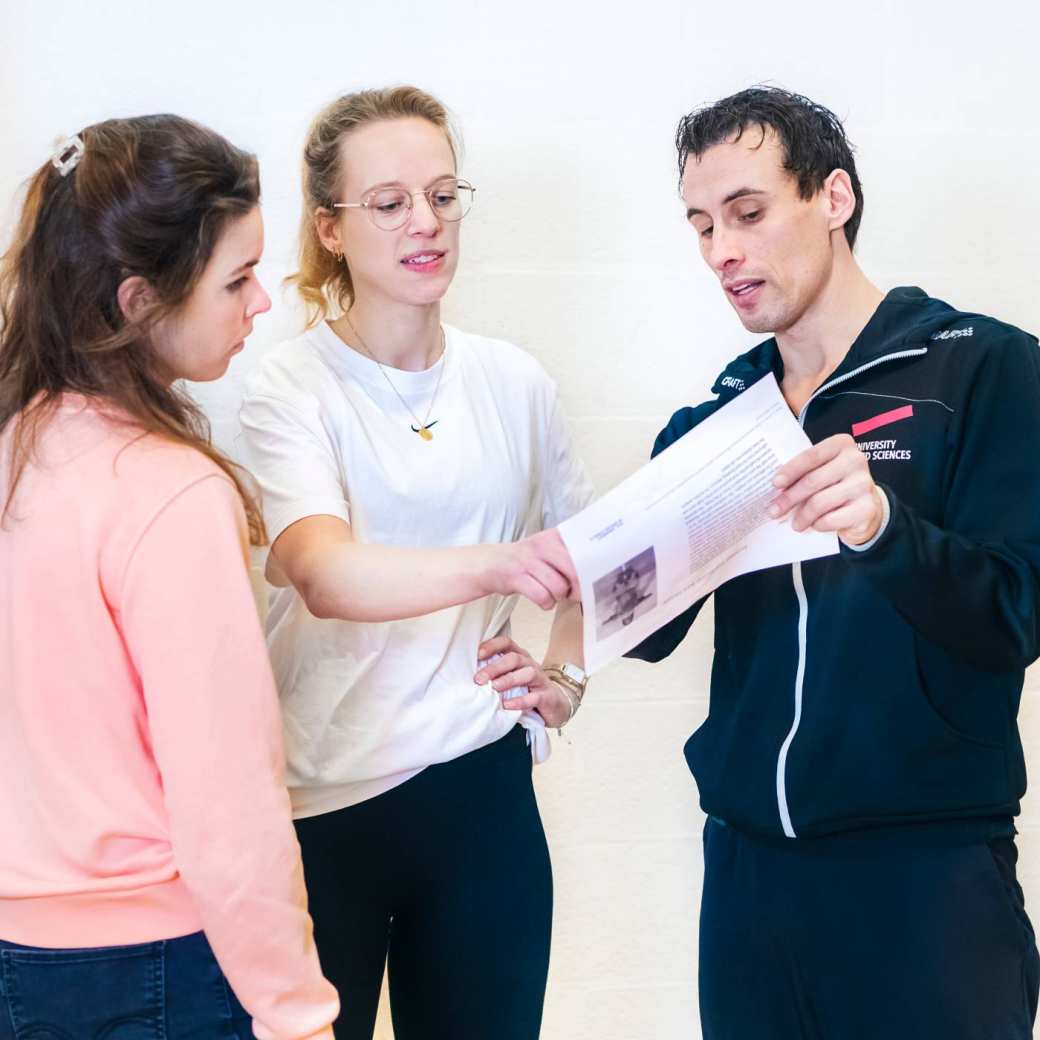 Docent helpt studenten en legt wat uit met behulp van een blaadje. 