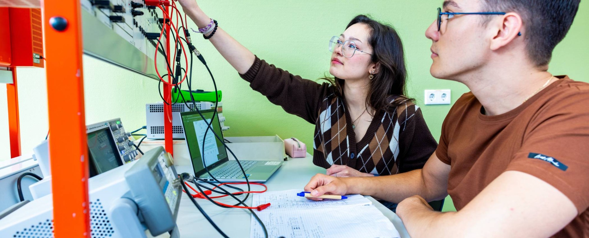 Twee studenten elektrotechniek werken samen tijdens een practicumsituatie.