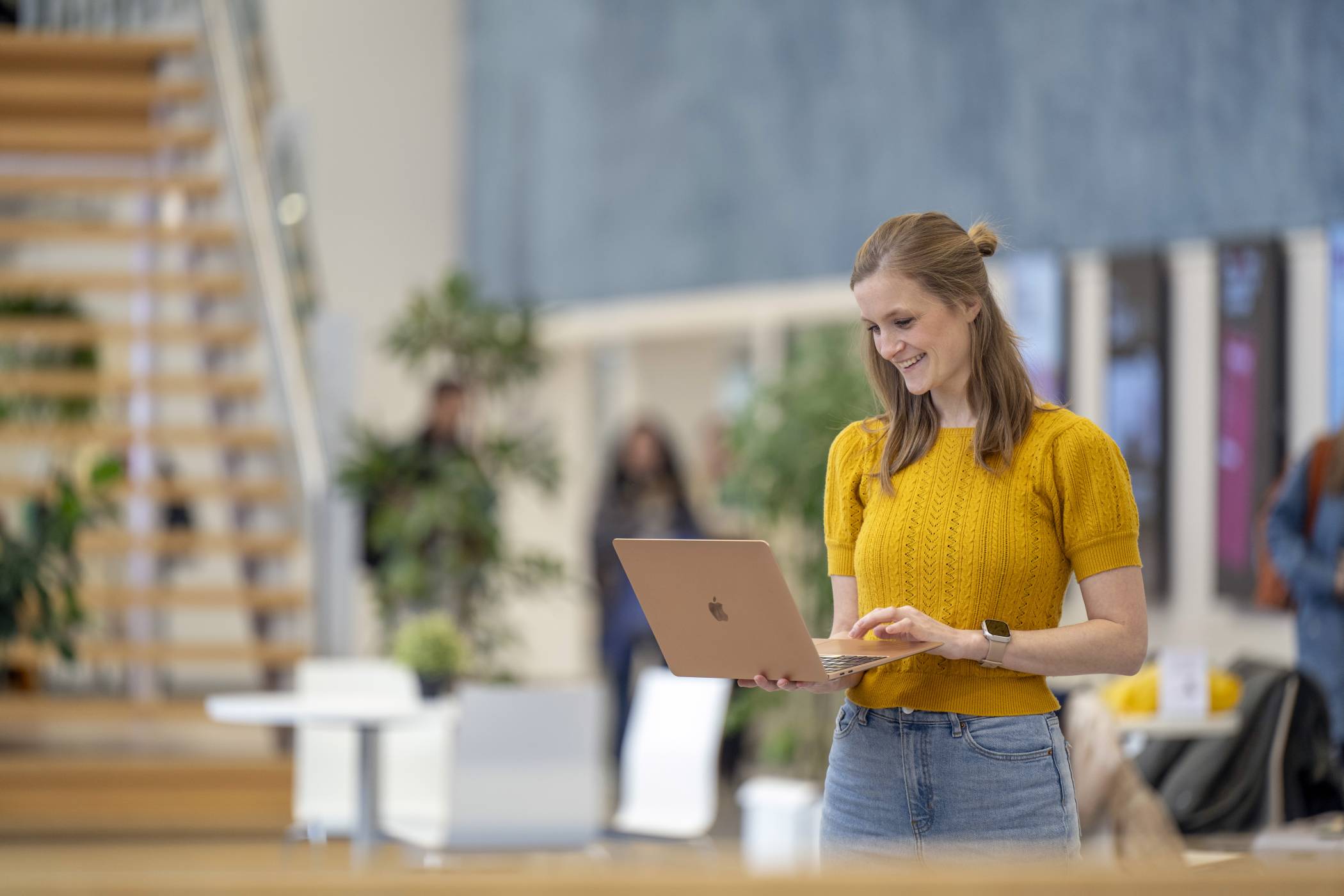 Student staat in een hal kijkend op haar laptop