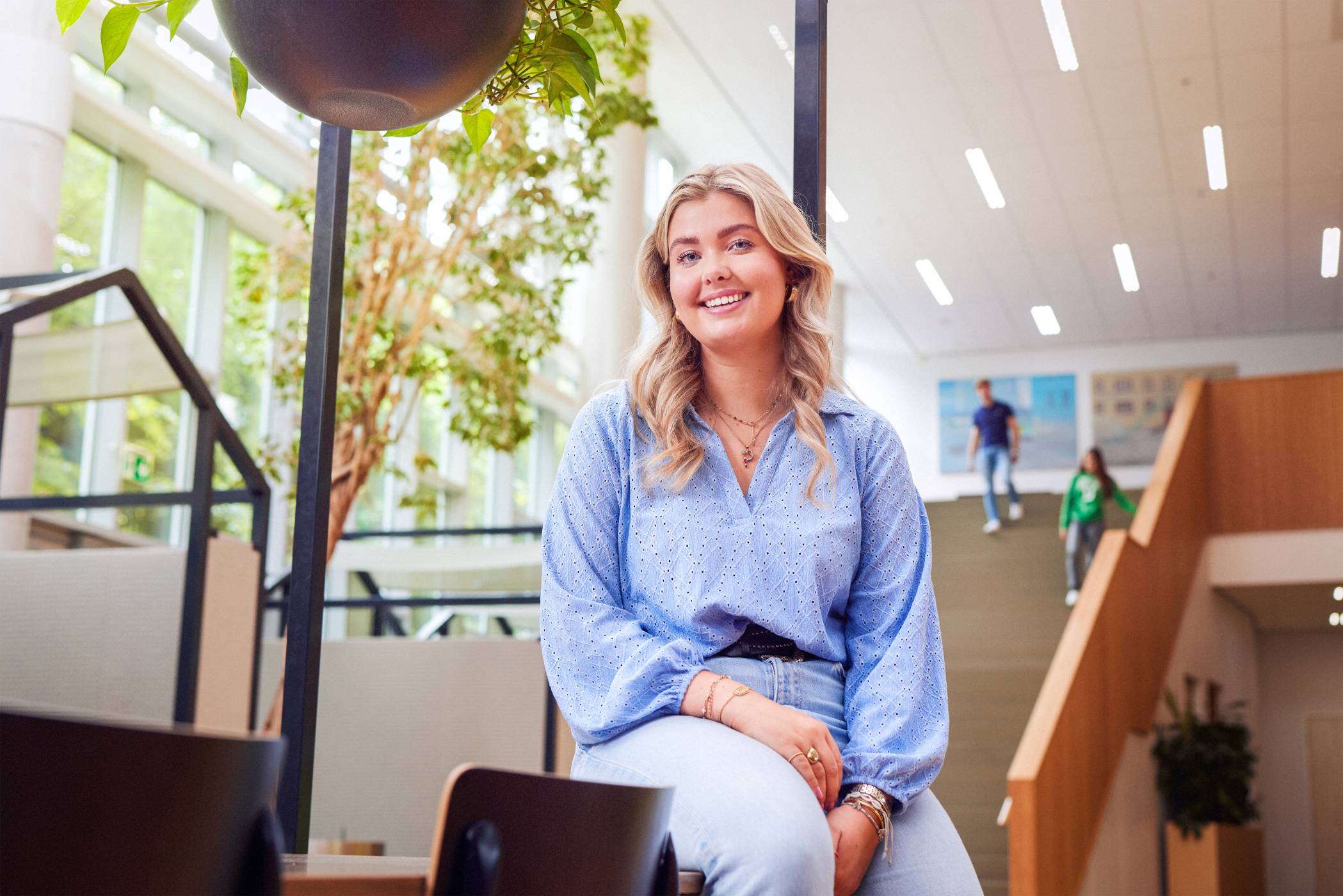 werving voltijd campagne, blonde studente met zachtblauwe blouse kijkt  lachend in de camera.